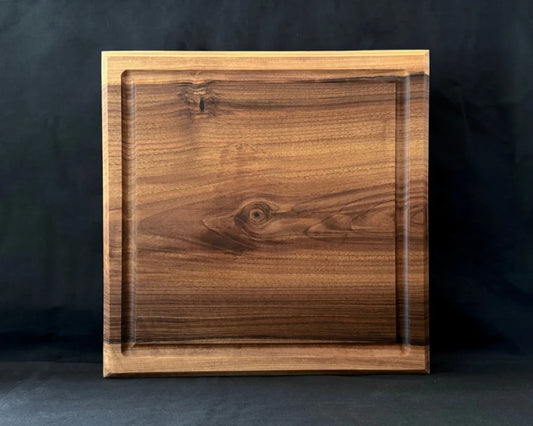 Massives Nussbaum-Schneidebrett 40 × 40 × 5 cm in frontaler Ansicht mit Saftrille und natürlicher dunkler Holzmaserung