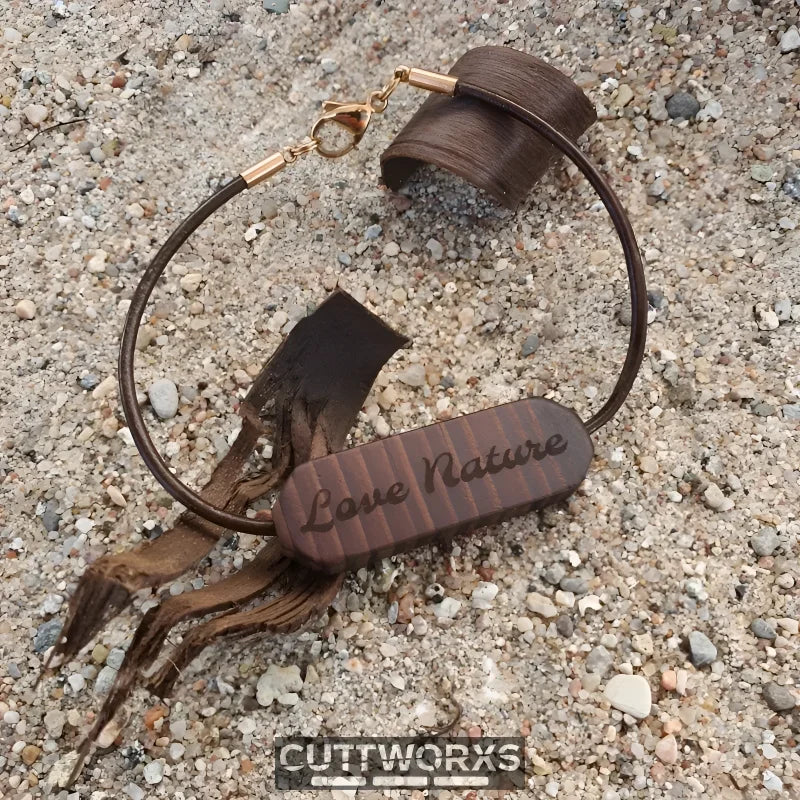 Braunes Lederarmband mit Wunschgravur und dekorativen Quasten auf texturiertem Untergrund