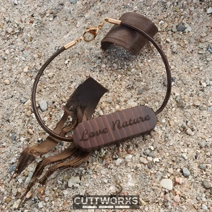 Braunes Lederarmband mit Wunschgravur und dekorativen Quasten auf texturiertem Untergrund