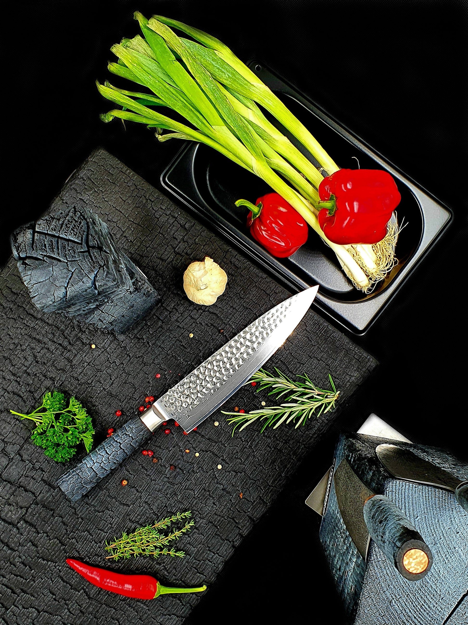 Damast Chefmesser mit gehämmerter Klinge schneidet Fleisch auf Walnussholzbrett – ergonomischer FlameWOOD Griff sichtbar