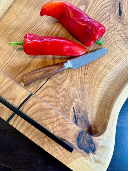 Zwei rote Paprika auf einem handgefertigten Eschenholz Servierbrett für die Küche