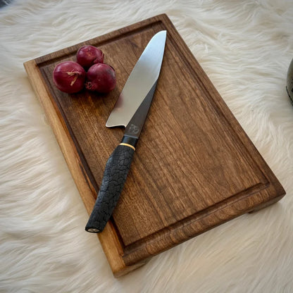 Holzschneidebrett aus Nussbaum Massivholz mit Kochmesser und roten Zwiebeln