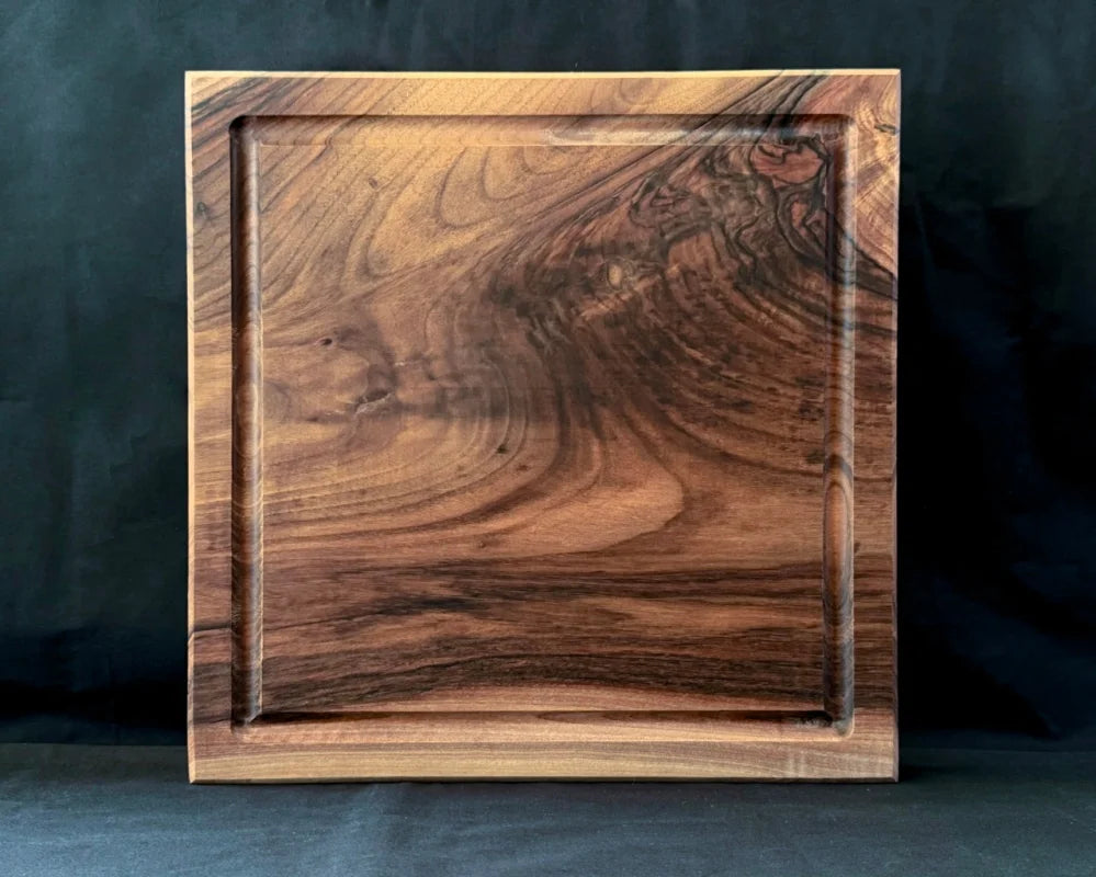 Massives Nussbaum-Schneidebrett 40 × 40 × 5 cm in frontaler Ansicht mit Saftrille und natürlicher dunkler Holzmaserung