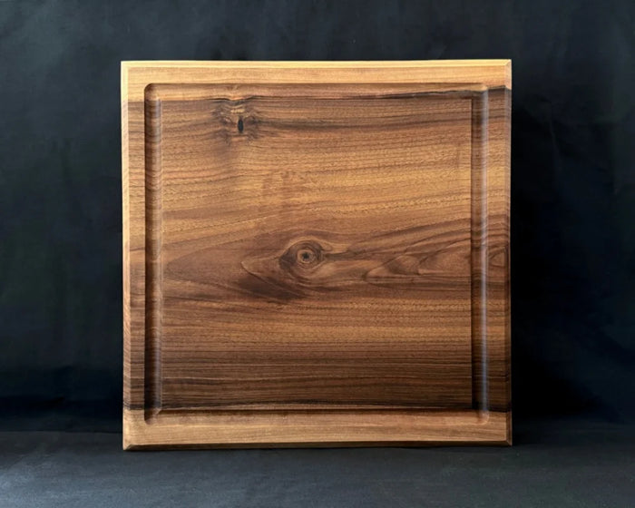 Massives Nussbaum-Schneidebrett 40 × 40 × 5 cm in frontaler Ansicht mit Saftrille und natürlicher dunkler Holzmaserung